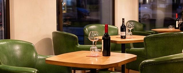 Piccolo wine bar lombardo con poltrone in pelle verde vicino a tavolini in legno