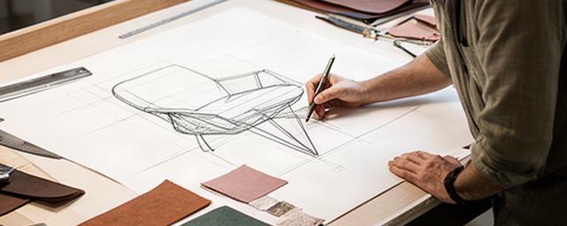 Designer italiano in studio mentre disegna una poltrona in pelle su tavolo tecnico