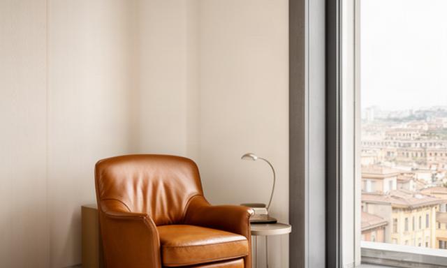 Poltrona in pelle color cuoio inserita in un angolo lettura di un attico a Milano