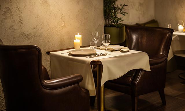 Piccola sala di ristorante gourmet con due poltrone in pelle attorno a un tavolo elegante